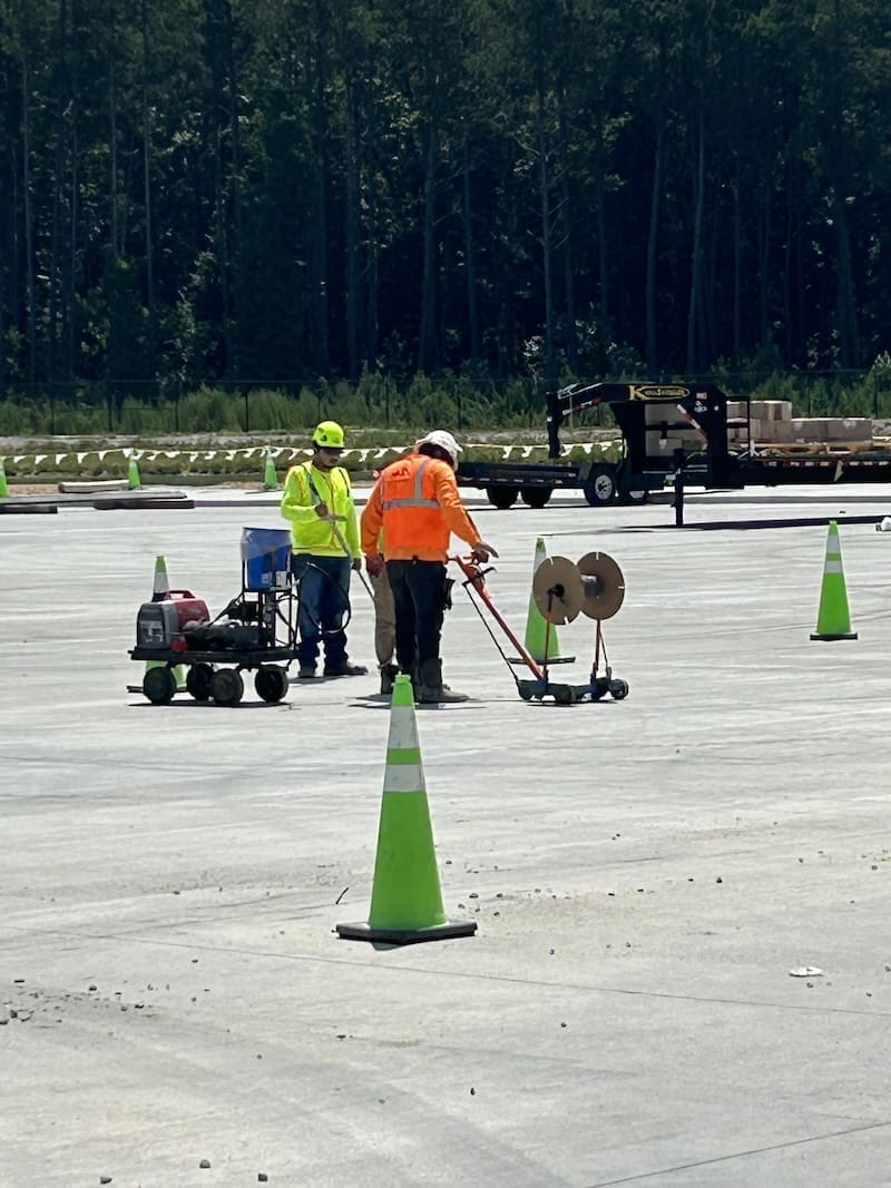 Two men prepping a parking lot to be resurfaced