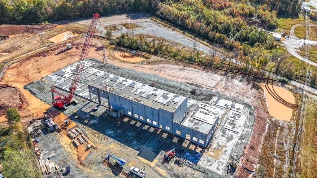 Drone view of a crane lifting a concrete tilt up wall